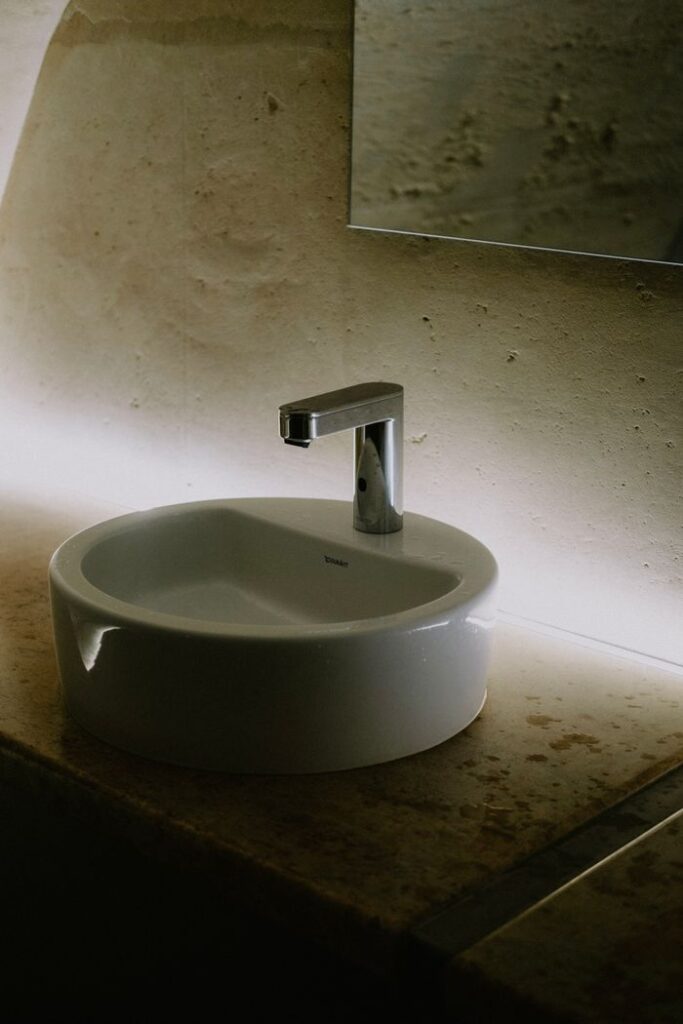 pexels-photo-11299685 Stylish bathroom sink featuring a sleek faucet and ambient lighting.