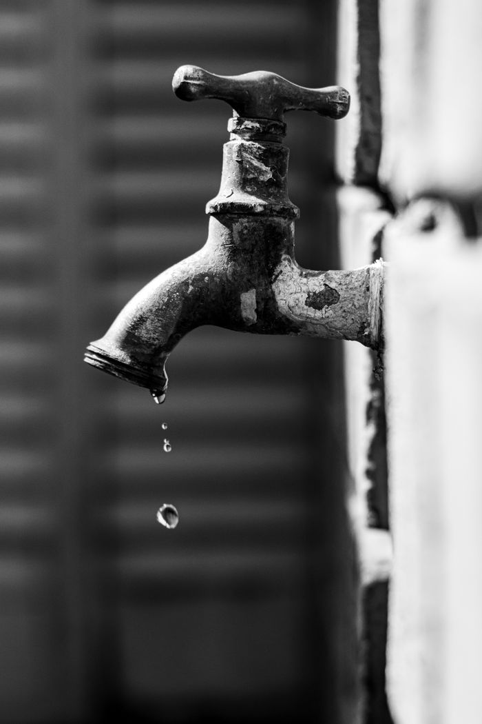 digital Black and white photo of a vintage water tap dripping water drops with a blurred background