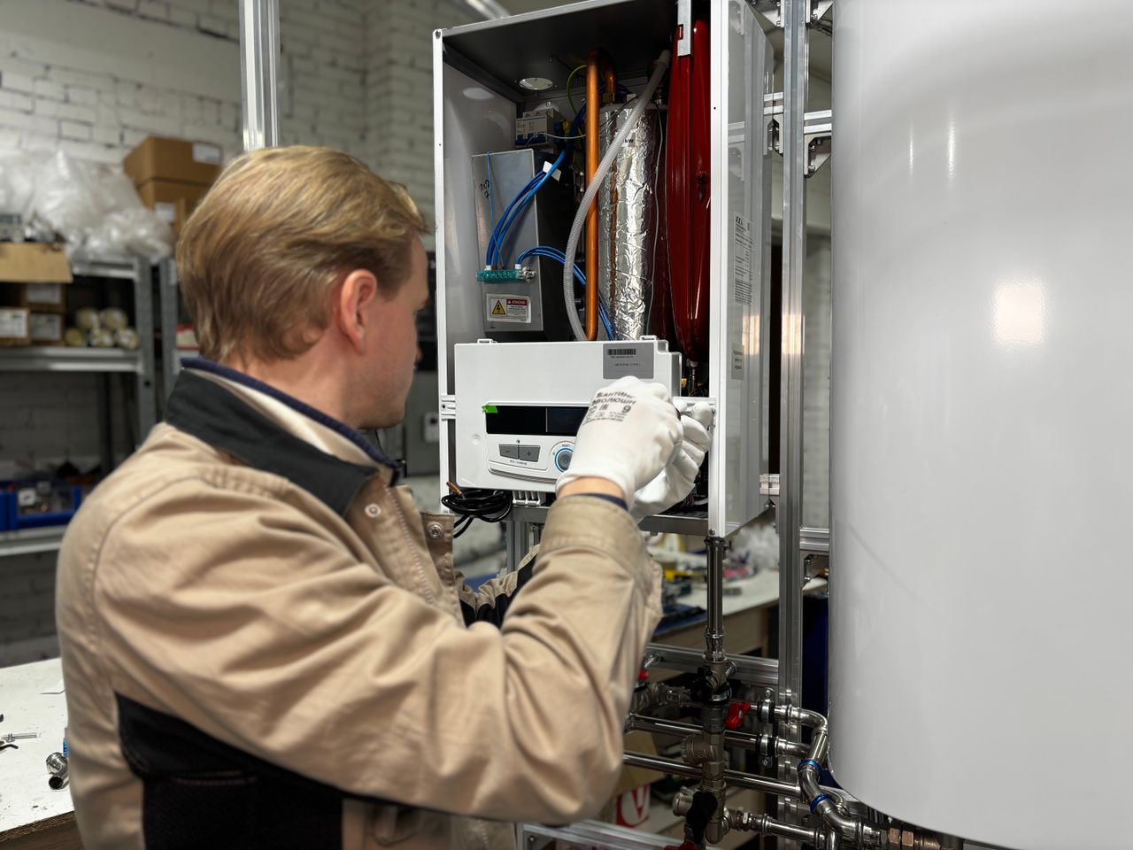 brand-03 Technician installing or repairing a heating system in an indoor workshop setting.