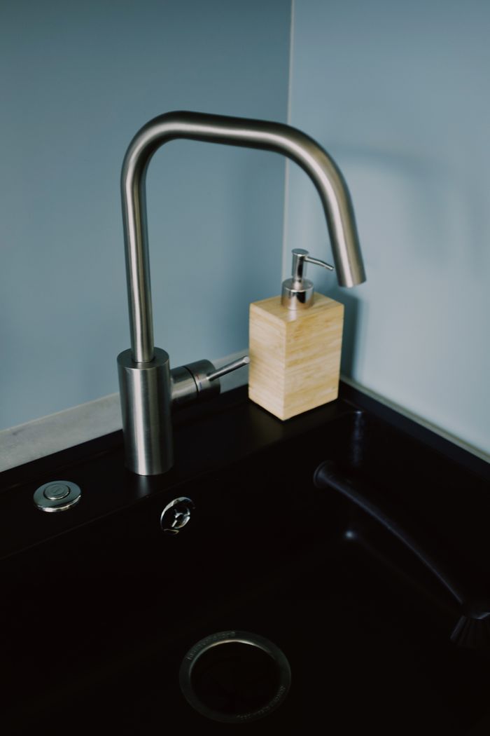 creative-02 Stylish kitchen setup featuring a stainless steel faucet and soap dispenser on a dark sink.